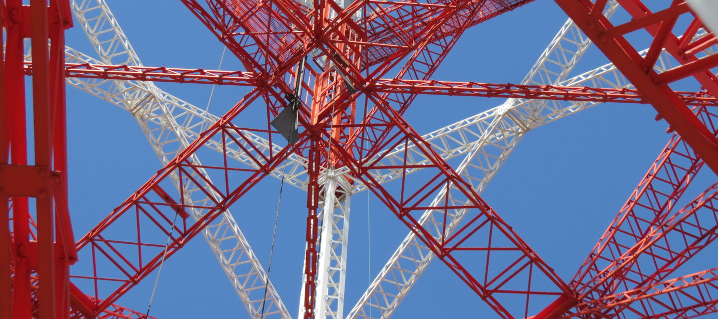 Blick in die Stahlkonstruktion eines rot-weißen Mastes. Beispiel für Mastbau-Projekte von Cteam. Blick in die Stahlkonstruktion eines rot-weißen Mastes. Beispiel für Mastbau-Projekte von Cteam.