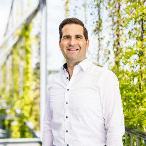 Homem de camisa branca sorri com fundo verde, transmitindo confiança e profissionalismo, ideal para representar a Cteam. Homem de camisa branca sorri com fundo verde, transmitindo confiança e profissionalismo, ideal para representar a Cteam.