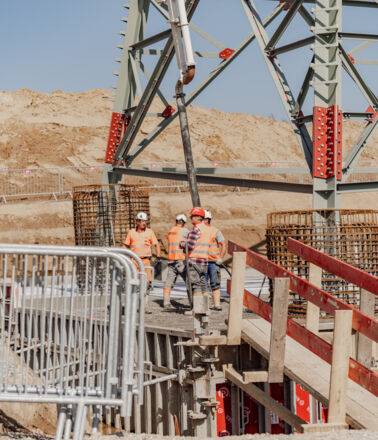 Workers pouring concrete for robust infrastructure foundations by Cteam. Workers pouring concrete for robust infrastructure foundations by Cteam.