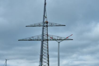 Freileitungsbau durch Cteam: Montagearbeiten an einem Gittermast nahe Windkraftanlagen. Freileitungsbau durch Cteam: Montagearbeiten an einem Gittermast nahe Windkraftanlagen.