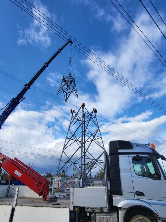 Cteam: Bau einer neuen Stromleitung mit Kran. Montage eines Strommastes durch Fachkräfte. Cteam: Bau einer neuen Stromleitung mit Kran. Montage eines Strommastes durch Fachkräfte.