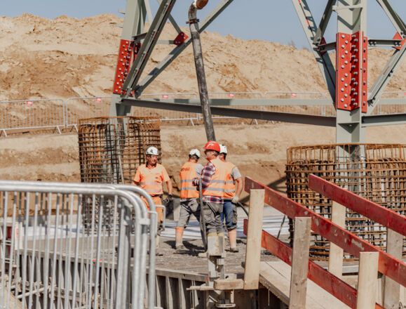 Engenheiros supervisionam concretagem de estrutura metálica, demonstrando expertise em projetos de construção civil para Cteam.