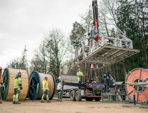 Cteam power infrastructure construction: Workers handle large cable reels and installation equipment. Cteam power infrastructure construction: Workers handle large cable reels and installation equipment.