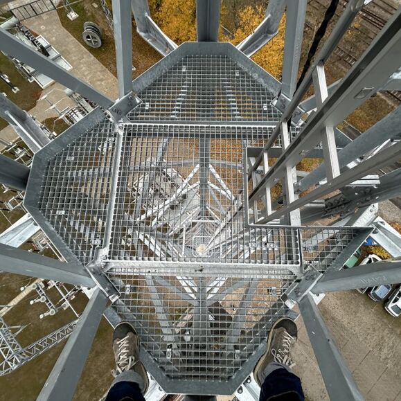Arbeit auf Höhe: Blick von einem Cteam-Gitterrost-Podest auf Stromleitungs-Infrastruktur. Arbeit auf Höhe: Blick von einem Cteam-Gitterrost-Podest auf Stromleitungs-Infrastruktur.