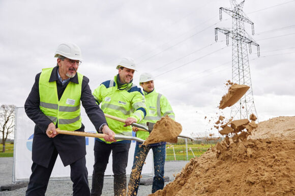 Spatenstich für ein Cteam Infrastrukturprojekt mit Strommasten im Hintergrund. Spatenstich für ein Cteam Infrastrukturprojekt mit Strommasten im Hintergrund.