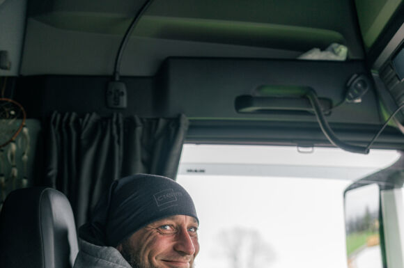 Motorista sorridente da Cteam em seu caminhão, pronto para seguir viagem.