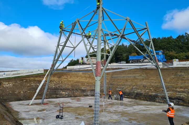 Baustellenansicht: Cteam Mitarbeiter montieren Gittermast für eine neue Hochspannungsleitung.